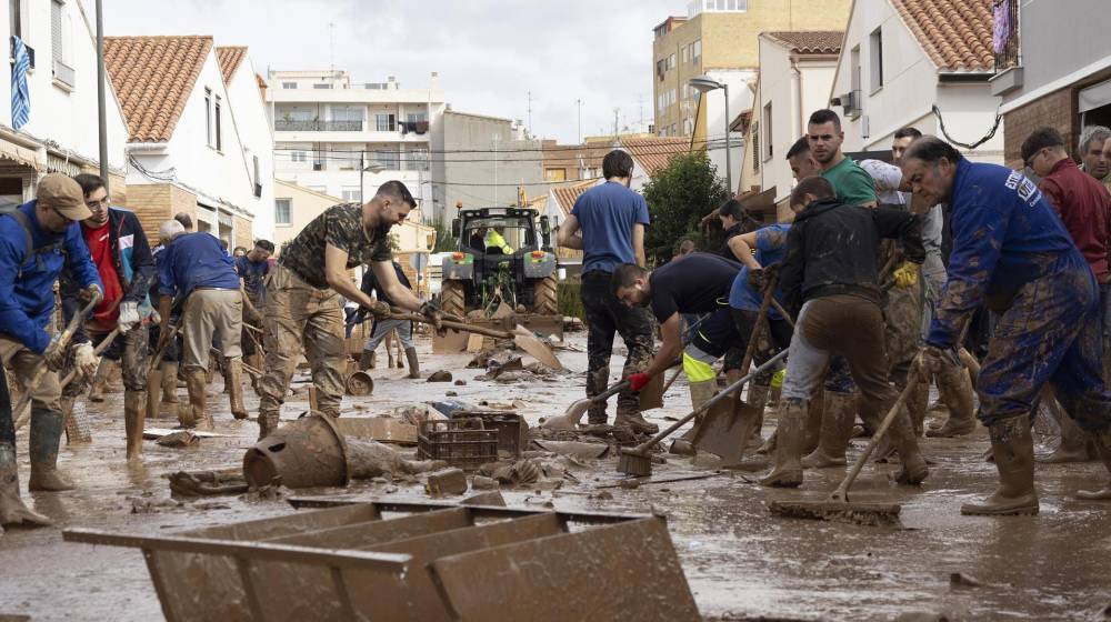 Varias personas colaboran en la limpeza de una calle afectada en la localidad de Utiel, este viernes 1 de noviembre.