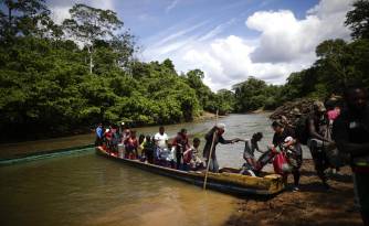 Fotografía de archivo de migrantes mientras descienden de una canoa antes de llegar a la Estación de Recepción Migratoria (ERM) de Lajas Blancas, luego de atravesar la selva del Darién.