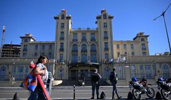 Una mujer pasa mientras oficiales de la Armada de Uruguay hacen guardia frente al Palacio del Mercosur antes de la sesión inaugural de la LXV Cumbre del Mercosur en Montevideo.