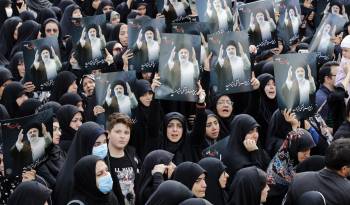 Mujeres iraníes vestidas con chadores negros sostienen carteles del difunto presidente iraní Ebrahim Raisi, mientras participan en una ceremonia de luto en Teherán, Irán, este lunes.