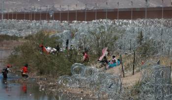 Migrantes llegan a una orilla del Río Bravo sembrada con alambre de púas en Cudad Juárez, Chihuahua (México).