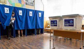 A Moldovan woman walks out of a booth to cast her ballot for the European Parliament elections, at a polling station in Chisinau on June 9, 2024.