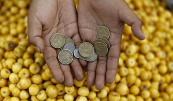 Fotografía de archivo en donde una vendedora de frutas muestra unas monedas en la central de abastos La Tiendona en San Salvador.