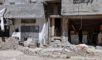 Una mujer observa desde la entrada de su casa, junto a una carretera dañada, tras una redada del ejército israelí en Tulkarem, en la Cisjordania ocupada, el 3 de agosto de 2024.