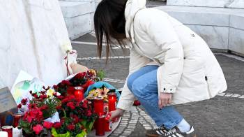 Una mujer coloca este jueves una vela en la estatua de Juan Pablo II ante el hospital Agostino Gemelli de Roma, donde el papa Francisco permanece hospitalizado.