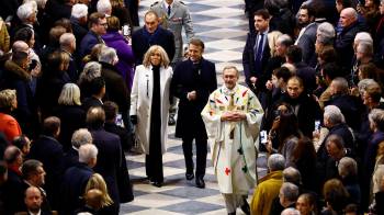 El presidente francés, Emmanuel Macron (D), y su esposa, Brigitte, llegan para asistir a la Misa inaugural, con la consagración del altar mayor, en la Catedral de Notre-Dame.