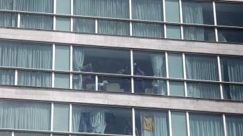 Migrantes hacen señas desde una ventana del hotel Decápolis este martes en Ciudad de Panamá, donde se mantienen tras ser deportados de EE.UU.