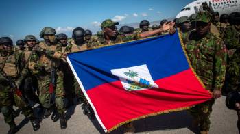 Policías kenianos sostienen una bandera de Haití a su llegada al aeropuerto internacional Toussaint Louverture este sábado, en Puerto Príncipe (Haití).