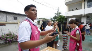 Funcionarios del Consejo Nacional Electoral (CNE) ofrecen información este 9 de febrero de 2025, en un puesto de votación en Olón, Ecuador.