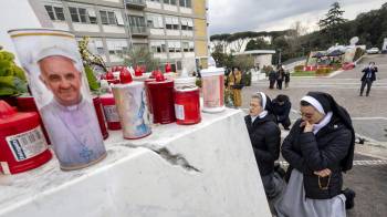 Dos monjas rezan ante la estatua del papa Juan Pablo II, en el policlínico Gemelli, donde el papa Francisco está hospitalizado, en Roma, Italia.