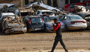 Un hombre camina junto a los coches apilados en Catarroja, Valencia este martes, una de las localidades más afectados por las inundaciones.