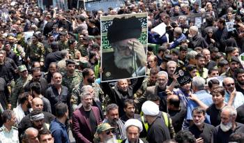 Los dolientes llevan un retrato del líder supremo de Irán, el ayatolá Ali Jamenei, durante el paso del funeral del presidente de Irán.