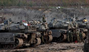 Soldados israelíes pasan junto a tanques estacionados en un campo al regresar a Israel tras un alto el fuego con Hizbulá, en Metula, en el norte de Israel.