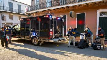 Investigadores del FBI llegan al lugar donde la camioneta blanca Ford F-150 se estrelló contra un elevador de trabajo, después de atropellar a una multitud en Año Nuevo.