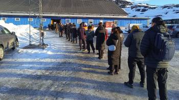 Vista general de una larga fila de votantes antes de ingresar al polideportivo Godthaabshallen, en la ciudad de Nuuk, para votar en las elecciones generales en Groenlandia.