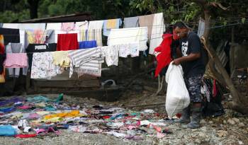 Un hombre recoge ropa en el poblado de Imias tras el paso de una tormenta tropical.