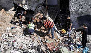 La gente busca entre los escombros de un edificio golpeado por un bombardeo en el campamento de refugiados palestinos de Nur Shams.