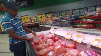 Un comprador compara los precios que tienen los jamones en uno de los supermercados de la localidad. El jamón es uno de los principales alimentos de la cena navideña de los panameños.