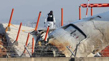 Un funcionario de un equipo de investigación científica de la Policía participa en la investigación en el lugar donde un avión se estrelló.