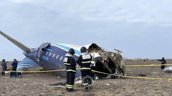 Miembros de los servicios de emergencias examinan los restos del avión de las líneas áereas de Azerbaiyán (AZAL) que se estrelló en el oeste de Kazajistán.