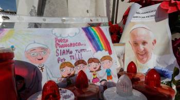 Un dibujo y una fotografía del papa Francisco bajo la estatua de Juan Pablo II, frente al Hospital Agostino Gemelli, donde se encuentra hospitalizado desde el 14 de febrero.