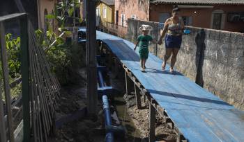 Personas caminan junto a un sistema de alcantarillado el 11 de junio de 2024 en una zona de la ciudad de Manaos, capital del estado de Amazonas (Brasil).