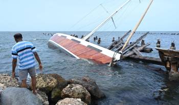 Un pescador observa a un barco hundido debido al paso del huracán Beryl este jueves, en Kingston (Jamaica).