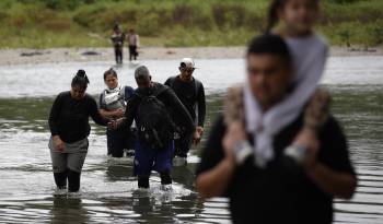 Foto de archivo de migrantes cruzando el río Tuquesa luego de atravesar la selva del Darién, en Panamá.