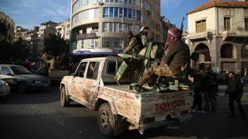 Rebeldes sirios en la parte trasera de un vehículo mientras la gente celebra en las calles de Homs, Siria.