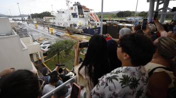 Personas observan el paso de un barco por una sección de las esclusas Miraflores del Canal de Panamá.