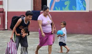 Habitantes de los campos bananeros caminan con sus pertenencias, este domingo en El Progreso Yoro (Honduras).