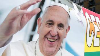 Las personas llevan una pancarta con una imagen del papa Francisco bajo la estatua del fallecido papa Juan Pablo II frente al Hospital Agostino Gemelli.