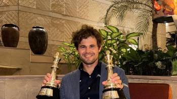 Magnus Carlsen posa con dos de sus trofeos.