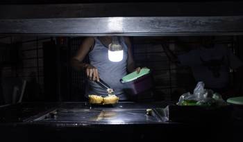 Una persona vende comida ayudado con un bombillo en medio de la oscuridad durante un corte eléctrico, el 29 de febrero de 2024 en Maracaibo (Venezuela).