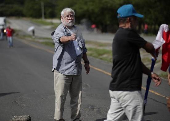 Un hombre dispara un arma hacia un manifestante en medio de un bloqueo de docentes en la vía Panamericana hoy, en Chame (Panamá).