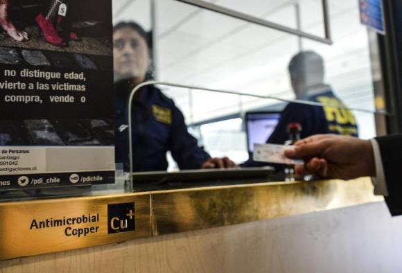 La policía personalizada revisa los pasaportes de viajeros que llegan a Chile, en un módulo protegido con cobre antimicrobiano en Santiago el 28 de agosto de 2016.