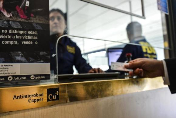 La policía personalizada revisa los pasaportes de viajeros que llegan a Chile, en un módulo protegido con cobre antimicrobiano en Santiago el 28 de agosto de 2016.