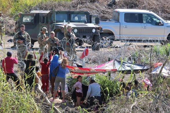 Migrantes son retenidos por La Guardia Nacional estadounidense al cruzar el Río Bravo para intentar ingresar a Estados Unidos hoy, en Matamoros