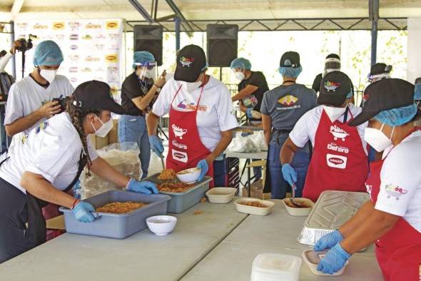 Voluntarios sirven los platos de arroz con pollo.