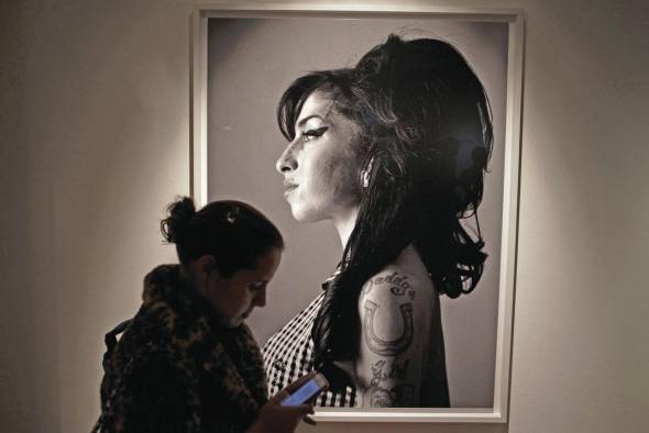 Un visitante pasa frente a un retrato de la fallecida cantante británica Amy Winehouse hecho por el cantante y compositor canadiense Bryan Adams.