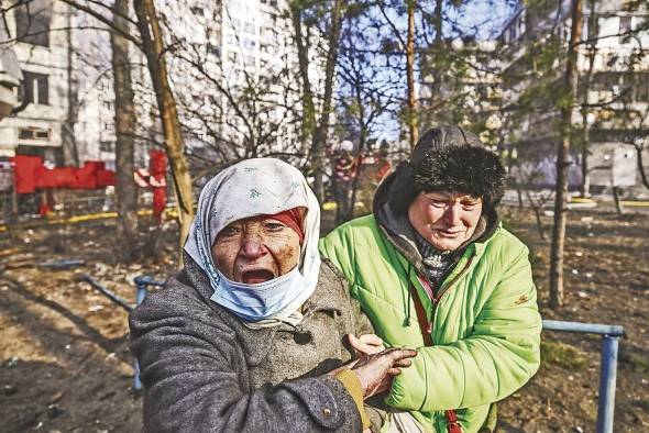 Una mujer es evacuada de un edificio de apartamentos en llamas, en Kiev, el 15 de marzo de 2022, después de que los ataques en áreas residenciales mataran al menos a dos personas, dijeron los servicios de emergencia de Ucrania.