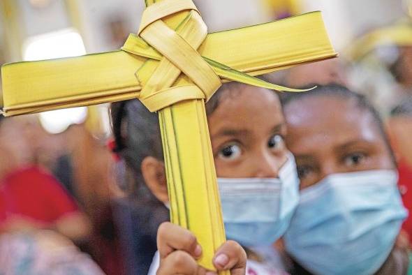 Una niña sostiene una cruz de palma durante la misa del Domingo de Ramos en el inicio de las festividades religiosas de Semana Santa, en Managua (Nicaragua).