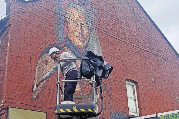 El joven artista indio Yash Patel, subido a una grúa, pinta un gran retrato del rey Carlos III del Reino Unido en el muro de una casa en el distrito de Hounslow (oeste de Londres).