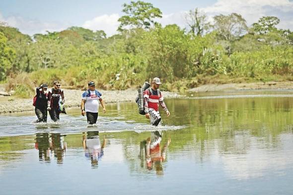 Personas migrantes cruzan el río Tuquesa, en Darién (Panamá).