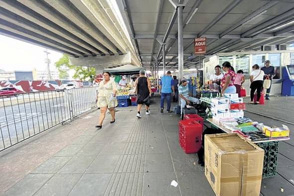 Puestos de buhoneros y peatones cerca de la parada de buses.