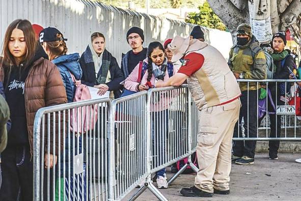 Integrantes del Instituto Nacional de Migración (INM) orientan a migrantes en el puerto fronterizo de San Ysidro, en la ciudad de Tijuana (México).