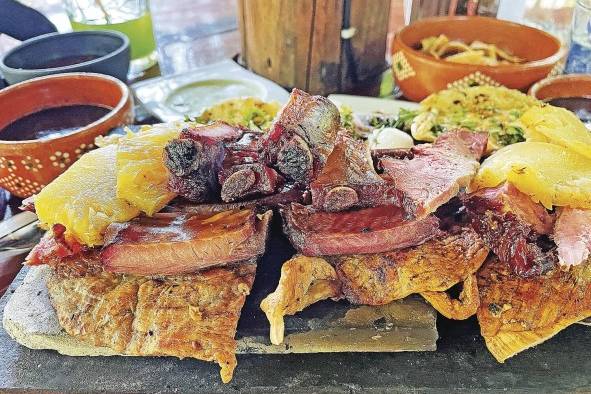 Vista de un platillo preparado con carne ahumada, longaniza y 'poc chuc', servido sobre una tabla el 23 de julio de 2022 en el restaurante Achiote, poblado de Tikuch, Valladolid, estado de Yucatán.