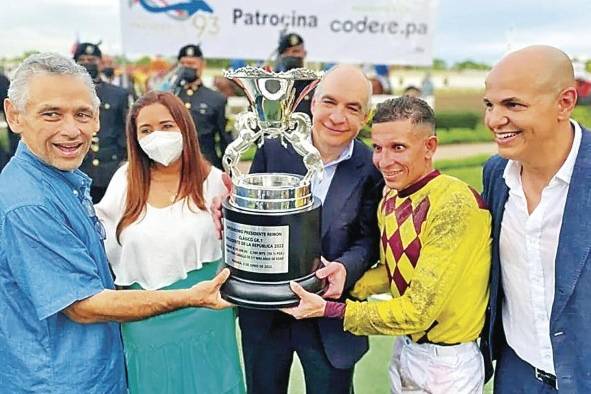 El propietario Isaac Tawachi, Germán Castillo (i) y Luis Arango sostienen la Copa del triunfo, junto a Carlos De Oliveira (d)