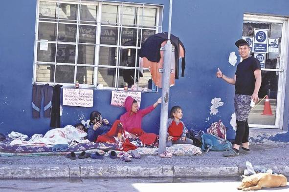 Una familia de personas pide ayuda en una calle, en una fotografía de archivo.