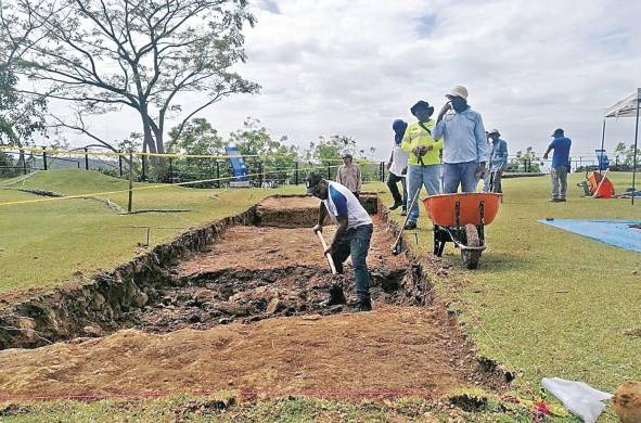 Trabajadores ayudan a recolectar la tierra de la excavación arqueológica.